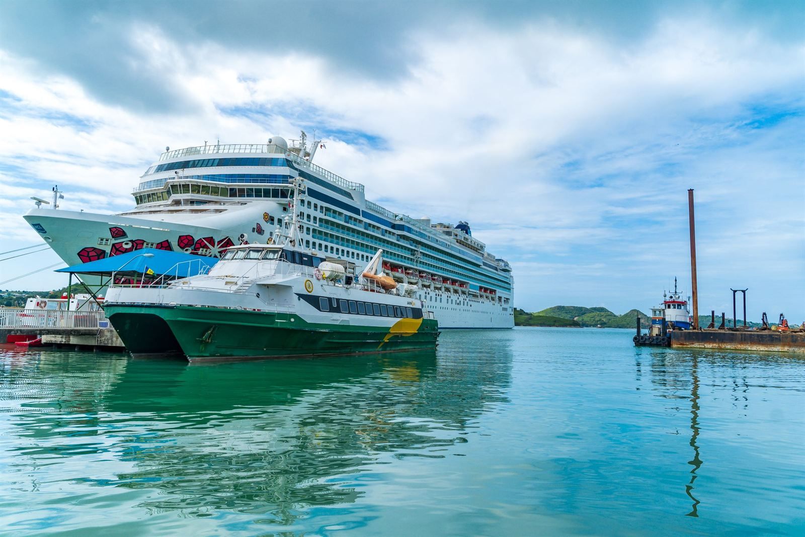 Cruise ship and a green-hulled ferry docked side by side in St. John's harbor, Antigua