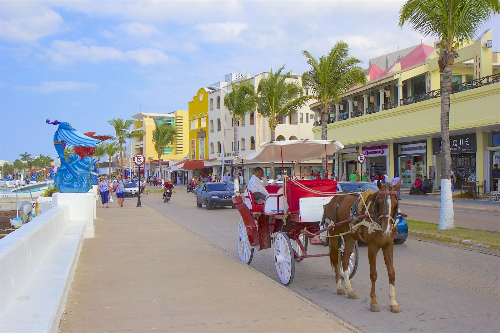 Horse-drawn carriage on the waterfront avenue in San Miguel, Cozumel, lined with palm trees and pastel shops