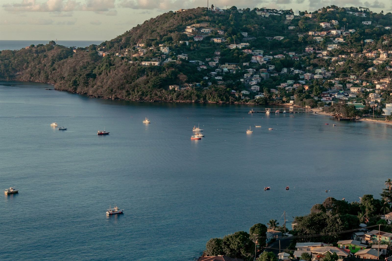 Hillside houses above a calm bay with small boats at anchor on Grenada