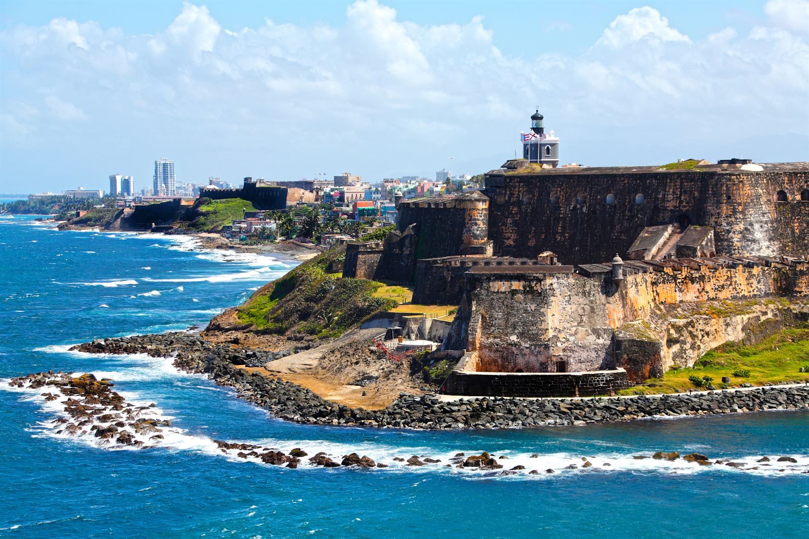El Morro fortress and lighthouse on the rocky shore of Old San Juan, with the city skyline behind