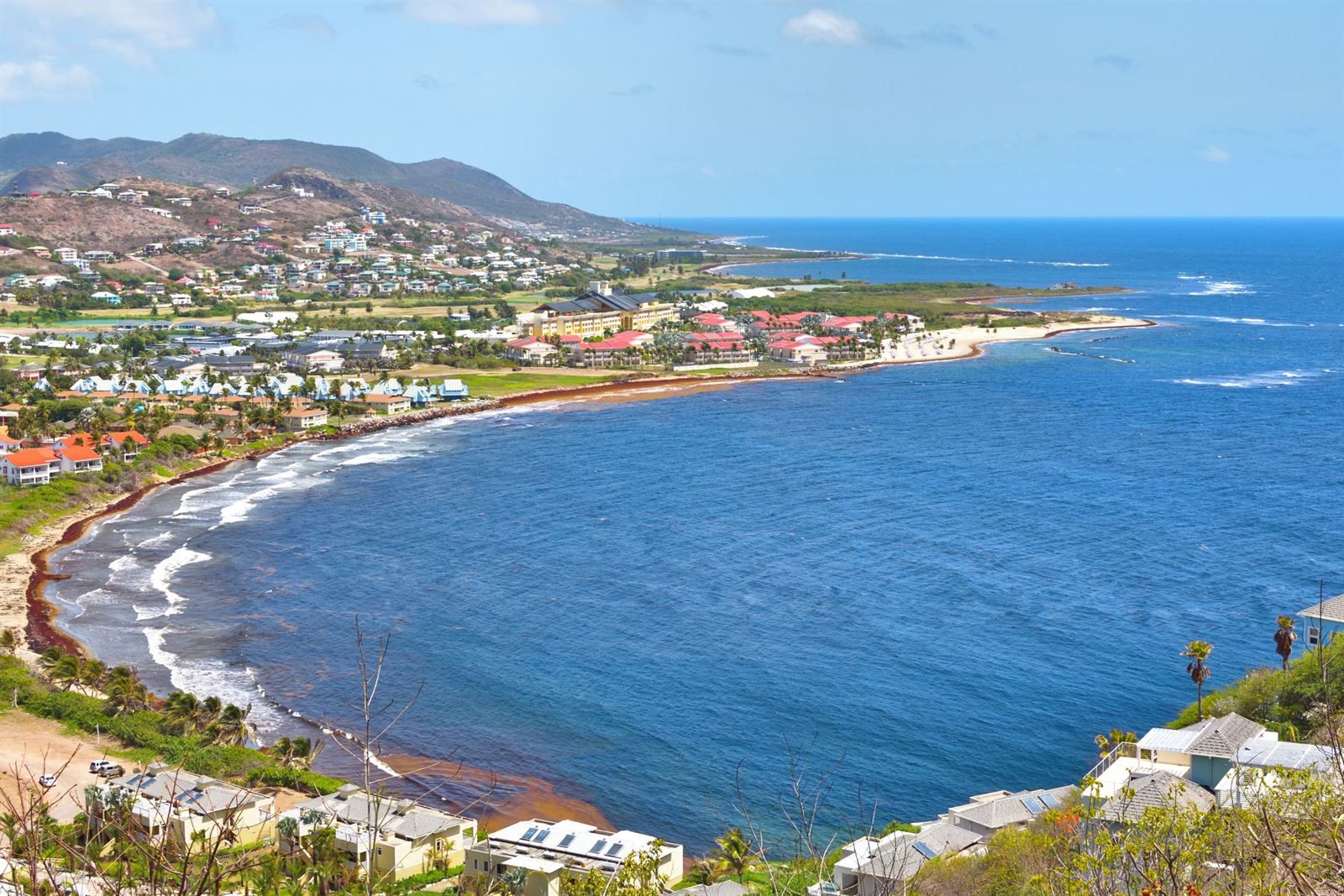 Curving bay with resorts and houses along the shore, seen from a hillside on St. Kitts