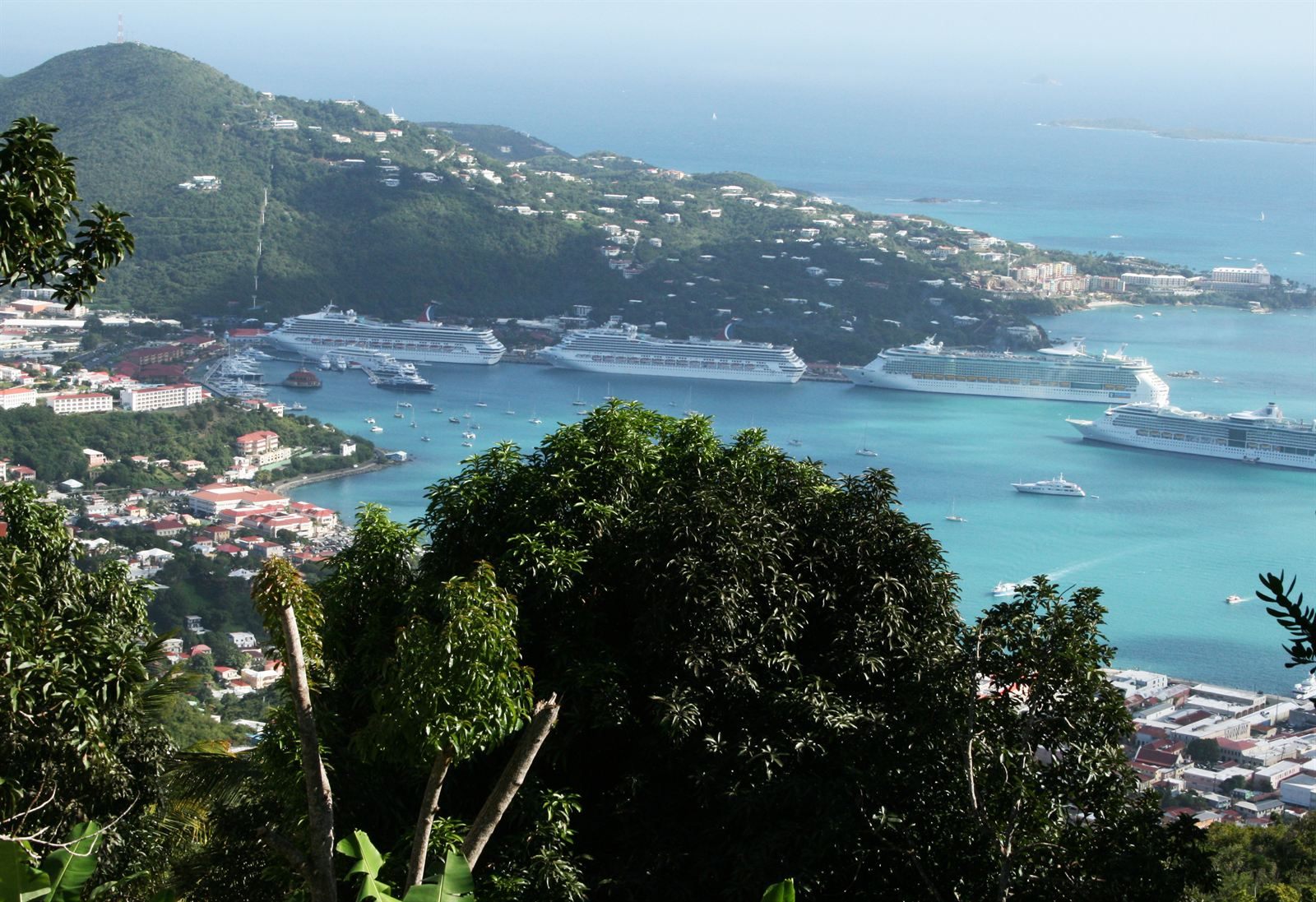 Four cruise ships docked in the harbor below the green hills of St. Thomas