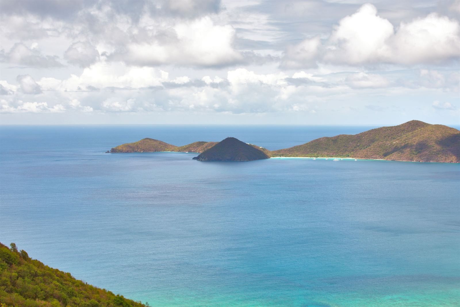 Hilly green islands rising from deep blue water, seen from a slope on Tortola